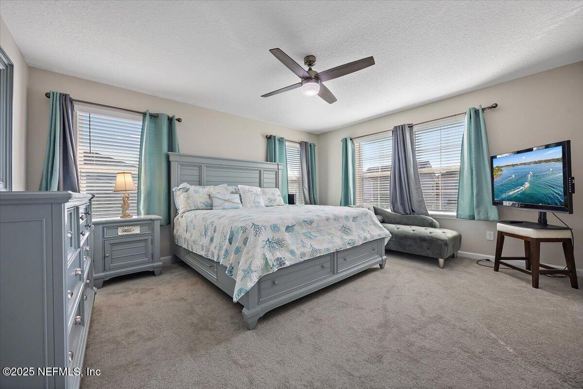 156 Clarys Run St. Augustine, FL 32092 - Photo 11 of 20 a bedroom with a bed a couch and a flat tv screen on dresser