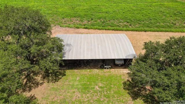 an aerial view of residential house with outdoor space and trees all around