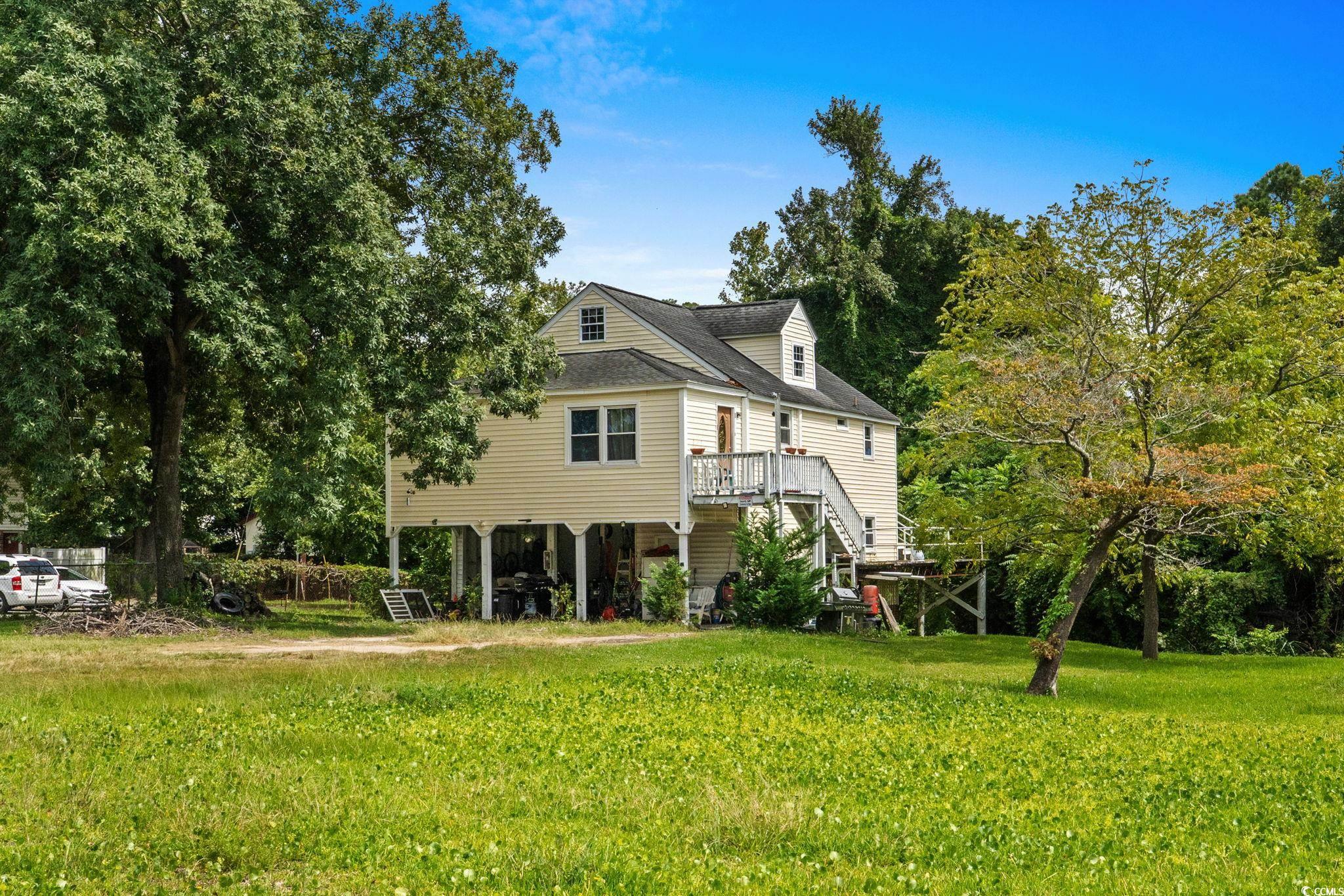 904 3rd Avenue North Myrtle Beach, SC 29577 - Photo 20 of 26 Back of house with stairway, a yard, a wooden deck, a shingled roof, and view of wooded area