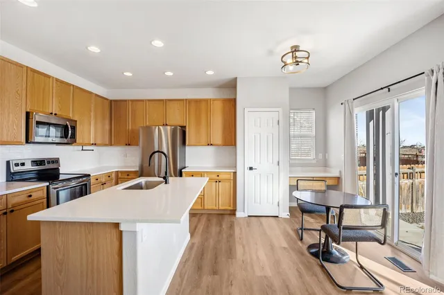 a kitchen with granite countertop a stove a sink a dining table and chairs