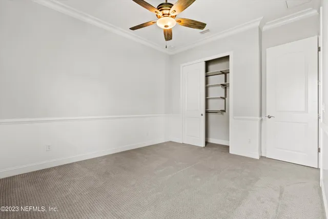 an empty room with closet and chandelier fan