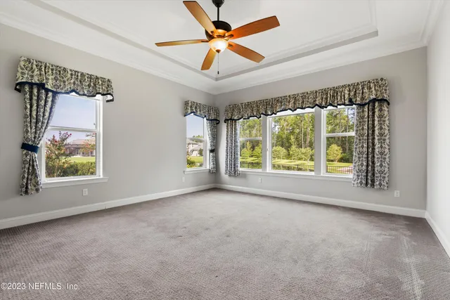 an empty room with windows and ceiling fan