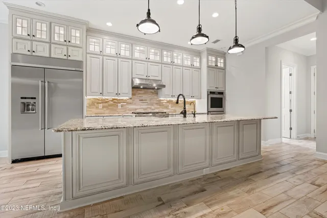 a kitchen with kitchen island granite countertop a sink cabinets and stainless steel appliances