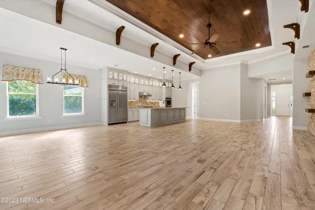 a view of an empty room and a kitchen