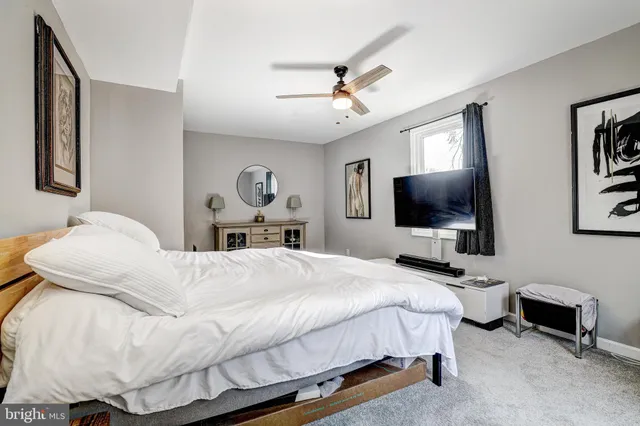 a bedroom with a bed couch tv and a window