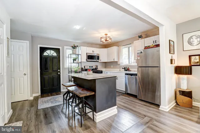 a kitchen with a refrigerator a microwave oven a sink dishwasher and white cabinets with wooden floor