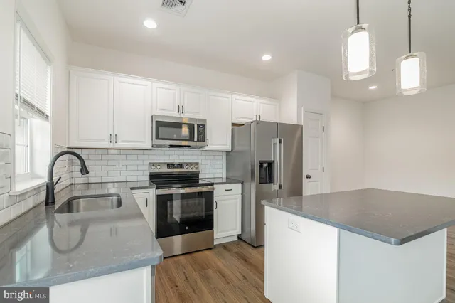 a kitchen with stainless steel appliances granite countertop a sink a stove a refrigerator cabinets and a center island