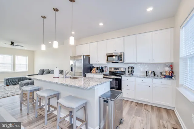 a kitchen with stainless steel appliances granite countertop a kitchen island a stove a sink a dining table and chairs