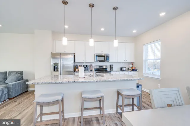 a kitchen with stainless steel appliances granite countertop a kitchen island a white cabinets a sink and a refrigerator