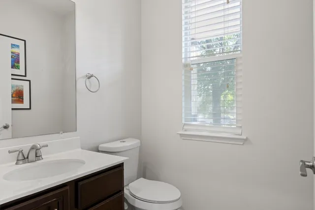 a bathroom with a toilet a sink a mirror and a window