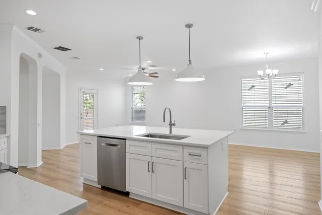 a kitchen with a sink chandelier and wooden floor