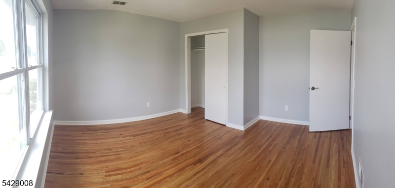 720 Walnut Street Linden, NJ 07036 - Photo 4 of 18 an empty room with wooden floor and windows