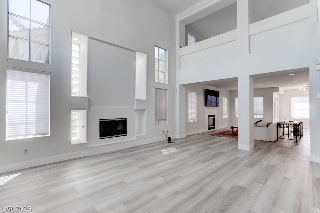 1 Rising Sun Court Henderson, NV 89074 - Photo 2 of 47 A spacious living room featuring high ceilings and light hardwood flooring, ready for personalization.