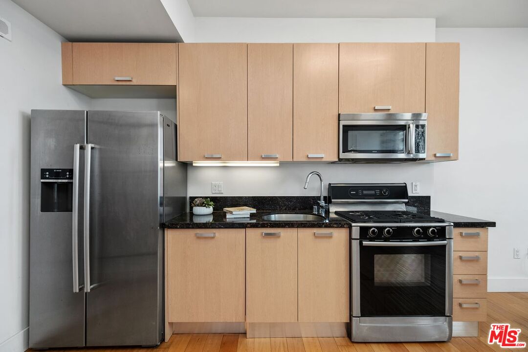 460 South Spring Street, Unit 1008 Los Angeles, CA 90013 - Photo 5 of 18 a kitchen with stainless steel appliances granite countertop a stove a refrigerator and a microwave