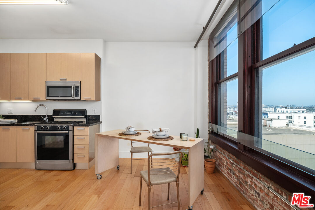 460 South Spring Street, Unit 1008 Los Angeles, CA 90013 - Photo 7 of 18 a kitchen with stainless steel appliances granite countertop a stove top oven a sink dishwasher a dining table and chairs with wooden floor