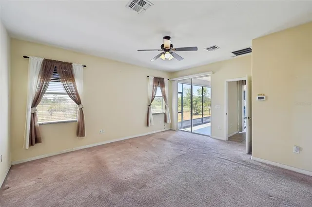 a view of empty room with window and ceiling fan