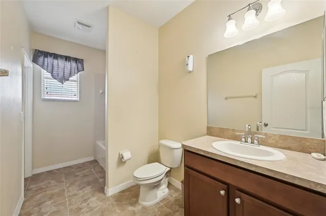 a bathroom with a granite countertop sink a toilet and a mirror