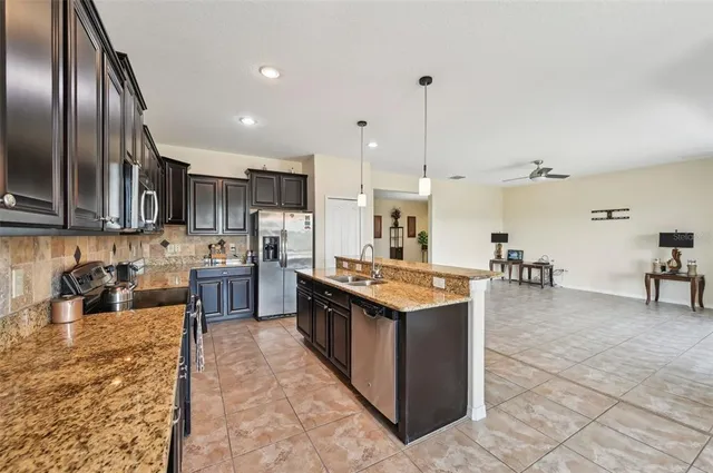 a kitchen with stainless steel appliances granite countertop a sink a stove and a refrigerator
