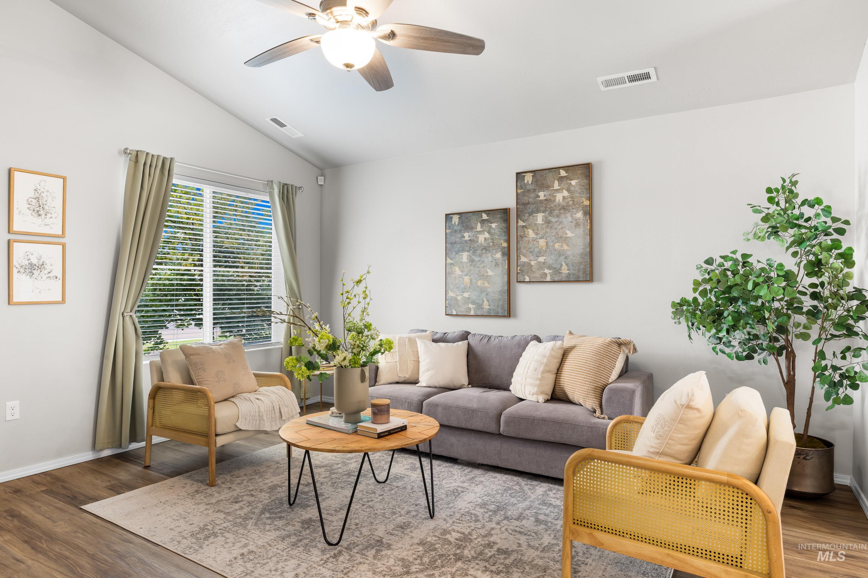 Living room with wood finished floors, vaulted ceiling, and ceiling fan