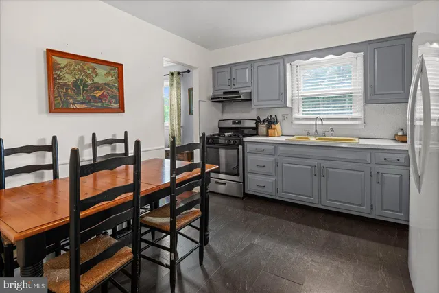 a kitchen with stainless steel appliances granite countertop a stove a sink a dining table and chairs