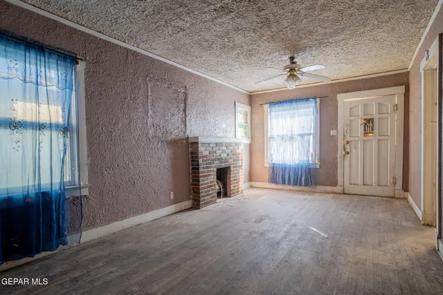 an empty room with windows and fireplace