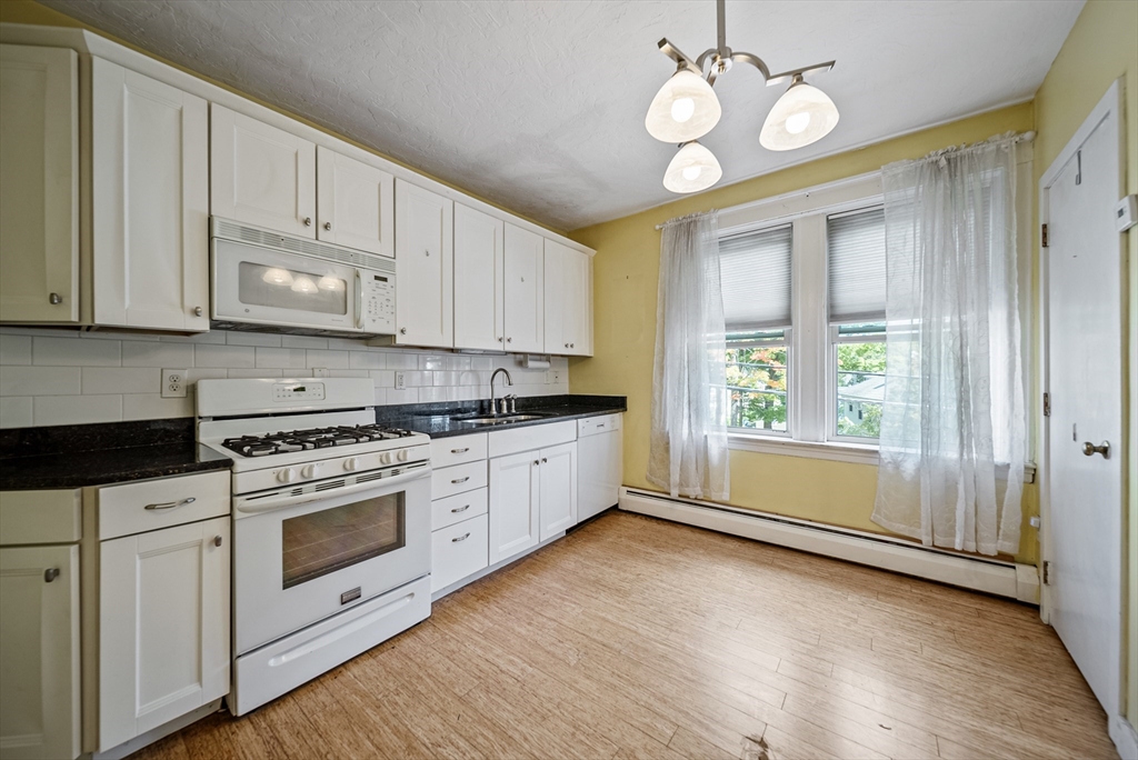 52 High Street, Unit 5 Methuen, MA 01844 - Photo 17 of 32 a kitchen with stainless steel appliances granite countertop a stove a sink and white cabinets with wooden floor