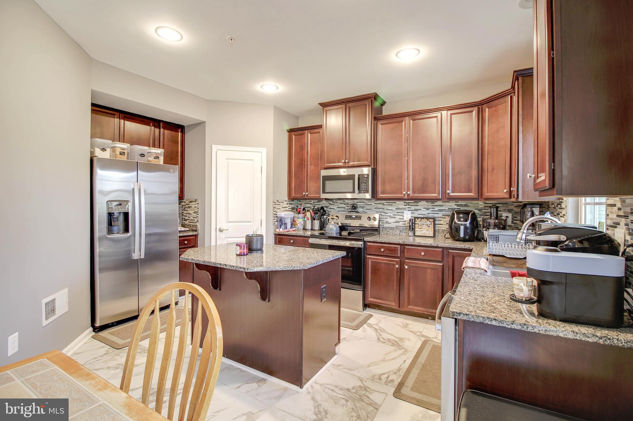 a kitchen with stainless steel appliances kitchen island granite countertop a sink stove and refrigerator
