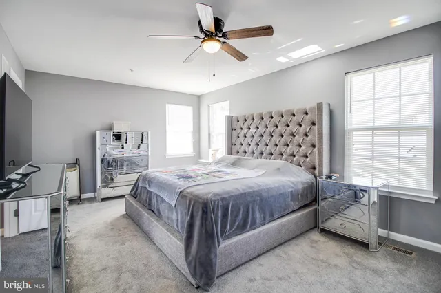 a spacious bedroom with a bed and a flat tv screen on the dresser