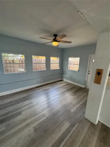 a view of an empty room with window and wooden floor