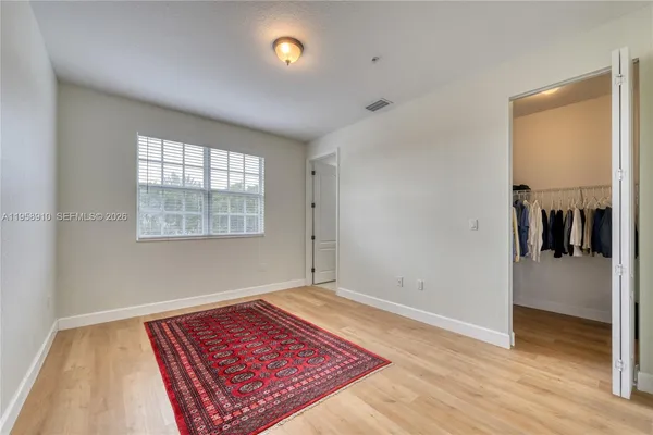 an empty room with wooden floor mirror and windows