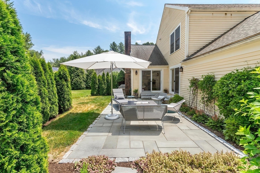 19 Edmonds Road Concord, MA 01742 - Photo 23 of 24 a view of a patio with couches table and chairs under an umbrella with a barbeque