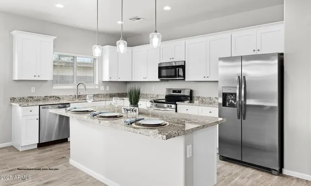 a kitchen with stainless steel appliances granite countertop a sink a stove a refrigerator and white cabinets