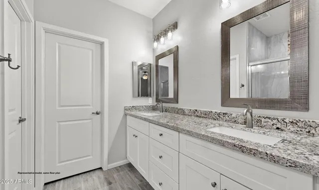 a bathroom with a granite countertop double vanity sink and two mirror