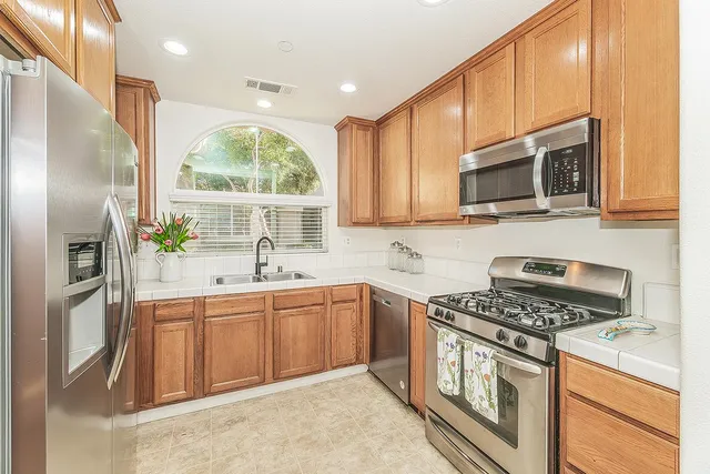 a kitchen with stainless steel appliances granite countertop a stove a sink and a microwave