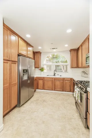 a large kitchen with stainless steel appliances double vanity and a refrigerator