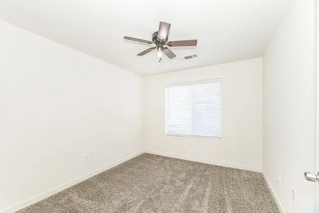 an empty room with windows and ceiling fan