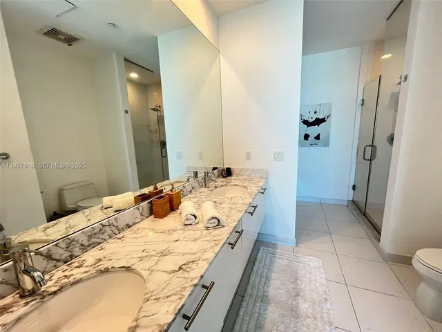 a bathroom with a granite countertop sink a toilet and shower