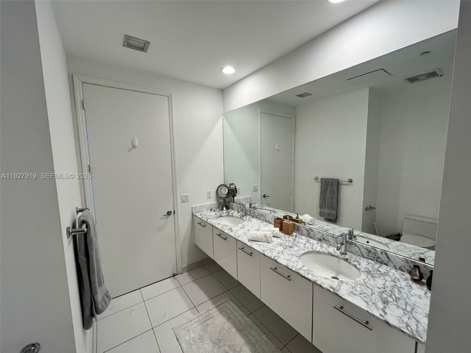 55 Southeast 6th Street, Unit 4103 Miami, FL 33131 - Photo 13 of 24 a bathroom with a granite countertop sink and a mirror
