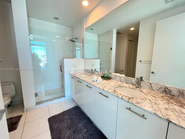 a bathroom with a granite countertop sink a mirror and a shower