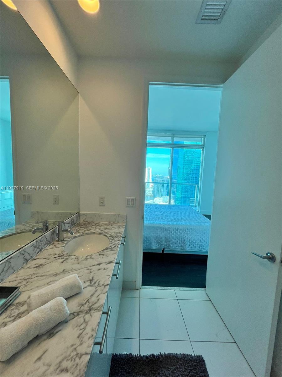 55 Southeast 6th Street, Unit 4103 Miami, FL 33131 - Photo 10 of 24 a bathroom with a granite countertop sink and a mirror