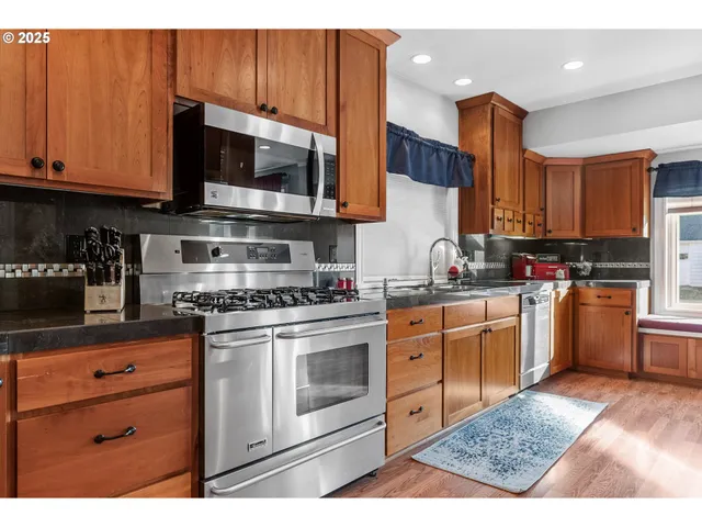 a kitchen with stainless steel appliances granite countertop a stove a sink dishwasher and a microwave oven with cabinets