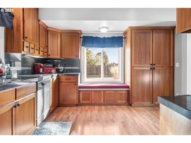 a kitchen with stainless steel appliances granite countertop a refrigerator a sink dishwasher and wooden cabinets with wooden floor