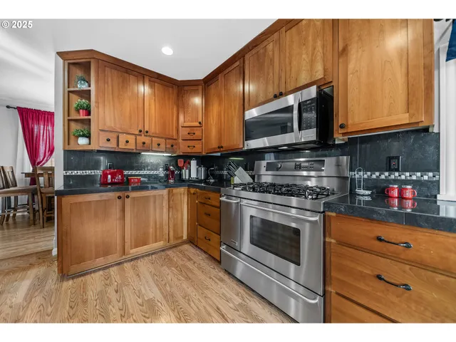 a kitchen with stainless steel appliances granite countertop a stove a sink and a microwave