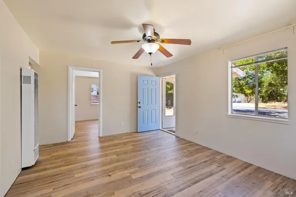 a view of empty room with wooden floor and fan