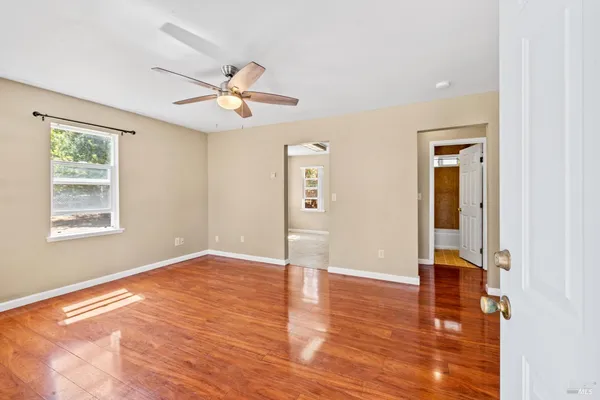 a view of an empty room with window and wooden floor