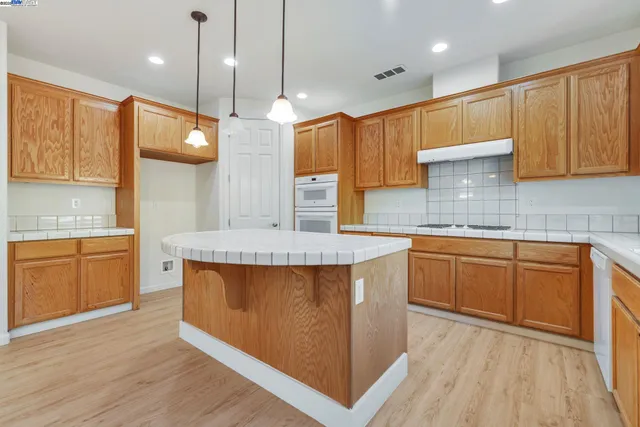 a kitchen with stainless steel appliances granite countertop wooden cabinets a stove a sink and a wooden floors
