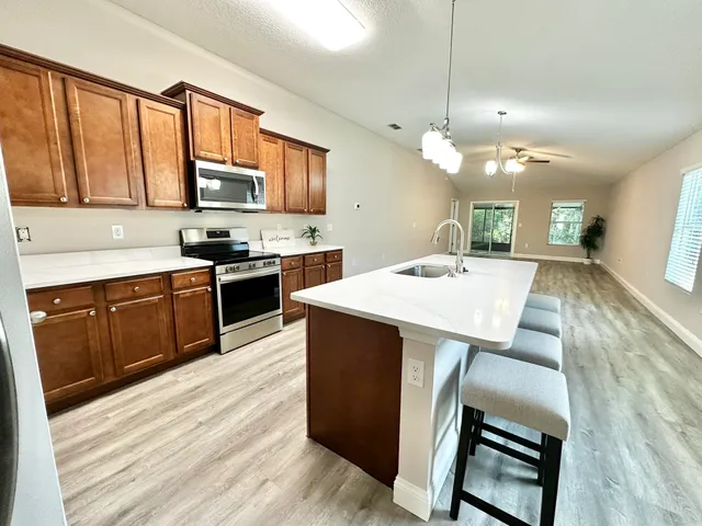 a large kitchen with stainless steel appliances kitchen island granite countertop a stove a sink dishwasher and a microwave with wooden floor