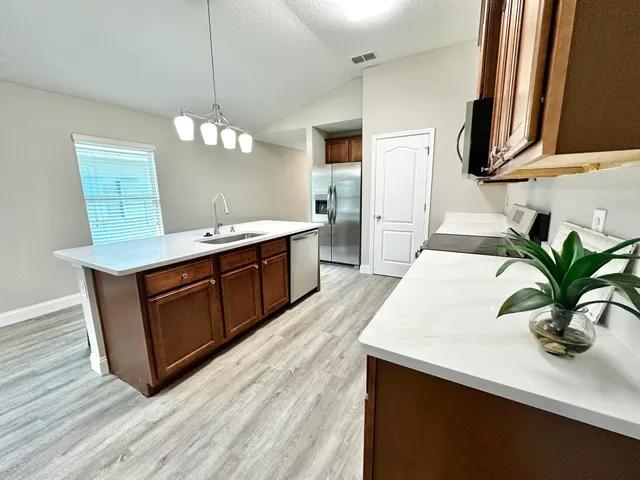 a kitchen with stainless steel appliances granite countertop a sink a stove and a wooden floor