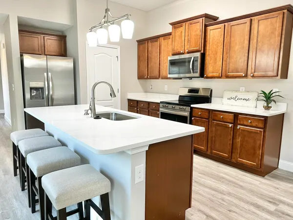 a kitchen with stainless steel appliances a sink a stove a refrigerator cabinets and dining table