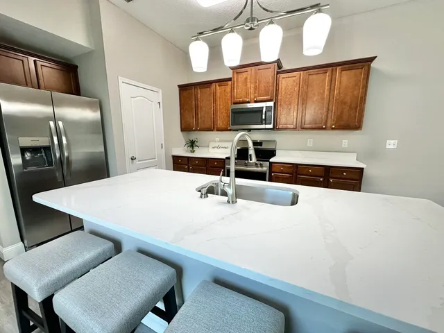 a kitchen with stainless steel appliances a stove a sink a microwave a refrigerator and cabinets